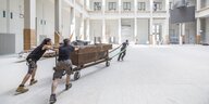 Drei Männer ziehen die Tür des Tresor-Clubs auf Rollen durch den Innenhof des Berliner Schlosses