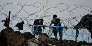Zwei Männer an einer Wasserleitung hinter Nato-Stacheldraht im Flüchtlingscamp Kara Tepe