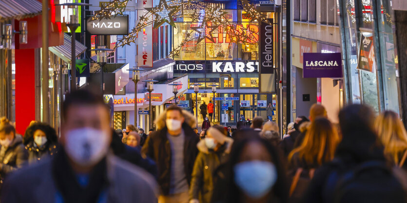 Viele Passanten mit Schutzmasken beim Weihnachtseinkauf auf der weihnachtlich geschmückten Limbecker Strasse in Essen