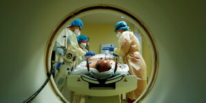Mitglieder des medizinischen Personals in Schutzanzügen behandeln einen Corona- Patienten vor einem Computertomographen auf der Intensivstation des Gemeindekrankenhauses Havelhoehe in Berlin