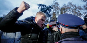 Ein Demonstrant in Tirana, Albanien hebt vor einem Polizisten wütend die Faust