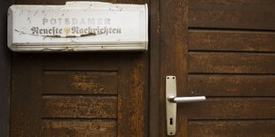 Alte verwitterte Holztür mit Zeitungsrohr der "Potsdamer Neuesten Nachrichten"