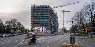 Hochhaus mit Kränen zwischen zwei großen Staßen