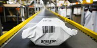 Ein mit Plastikfolie umhülltes Amazon-Paket auf einem Fließband
