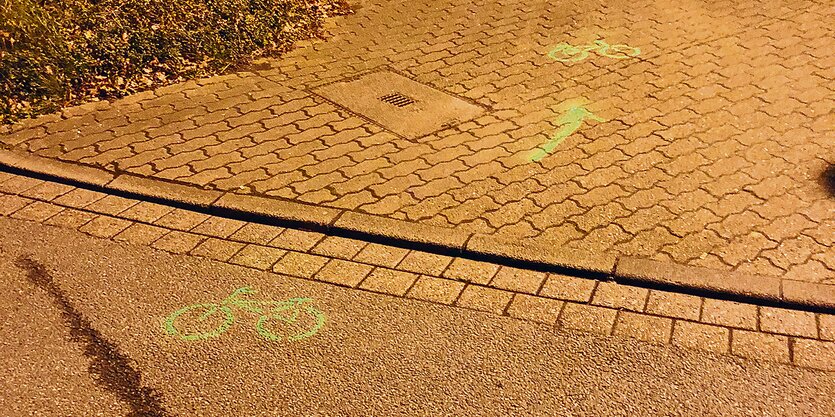 Ein mit grüner Farbe auf eine Straße aufgesprühtes Bild eines Fahrrads.