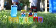 Kinder-Spielfiguren auf Spielsteinen mit der Aufschrift "Covid 19"