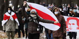 Demonstranten mit Mund-Nasen-Schutz tragen Fahnen in den Farben der früheren belarussischen Nationalflagge