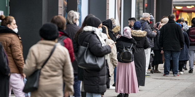 Das Bild zeigt, wie Menschen in einer langen Reihe vor einem Geschäft am Ku'damm anstehen.