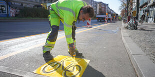 Mann sprüht Fahrradsymbol auf Straße