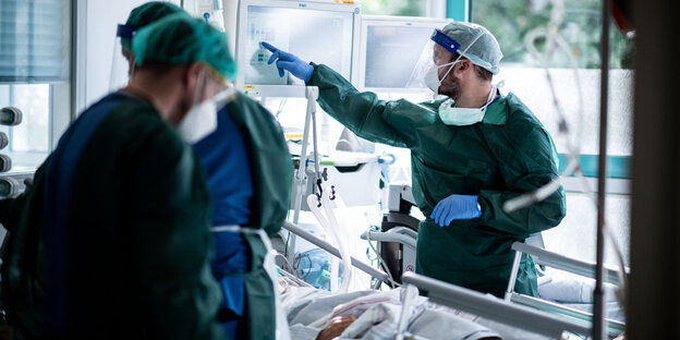 Mitarbeiter der Pflege in Schutzkleidung behandeln einen Patienten mit Corona-Infektion auf der Intensivstation in einem Krankenhaus in Essen