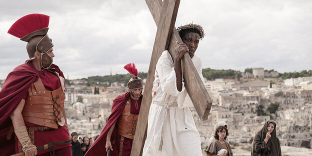 Jesus, gespielt vom schwarzen Schauspieler Yvan Sagnet, mit dem Kreuz, im Hintergrund die Stadt Matera.