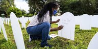 Eine Trauernde bemalt einen Grabstein für einen verstorbenen Verwandten