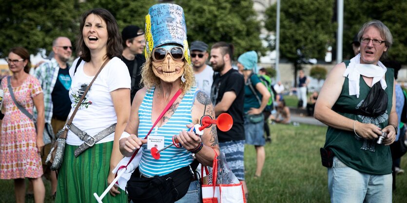 Mit Brille und Totenmaske verkleidet und Spritzen in der Hand verkleidete Demonstrantin