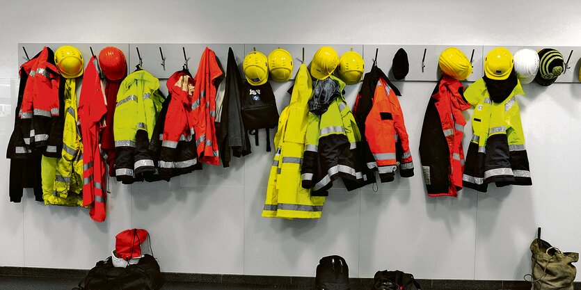 Arbeitsjacken hängen an einer Garderobe.