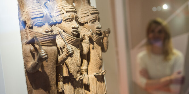 Raubkunst-Bronzen – in Relief mit drei stilisierten Menschenfiguren – aus dem Land Benin in Westafrika sind im Hamburger Museum für Kunst und Gewerbe (MKG) in einer Vitrine ausgestellt