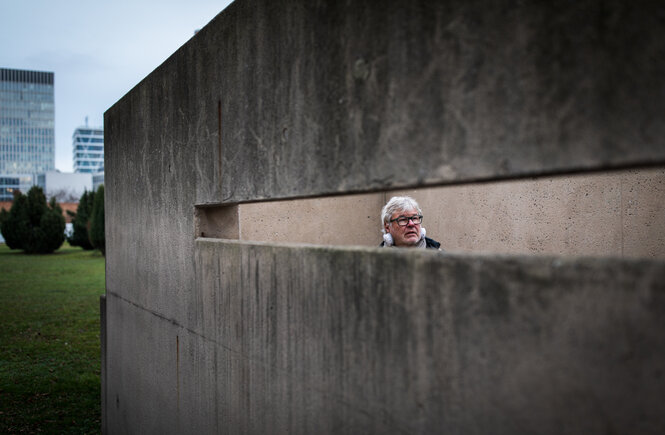 Eine Betonwand mit einer schmalen langen Aussparung: Der Autor Uwe Rada ist beim Audiowalk auf den Spuren von Albrecht Haushofer zu sehen