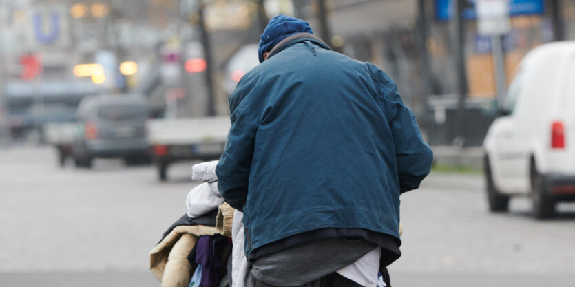 ein Mensch fährt sein Hab und Gut auf einem Wagen durch die Stadt