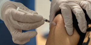 Eine Impfspritze in einem Oberarm.