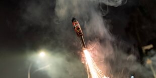 Eine Feuerwerksrakete hebt in den dunklen Himmel ab