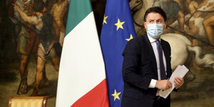 Italiens Ministerpräsident Giuseppe Conte mit Maske vor einer italienischen und einer Europa-Fahne