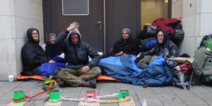Junge Obdachlose sitzen auf dem Fußweg vor einer Tür