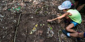 Kind bastelt eine Eule auf einem Waldboden