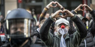Demonstranten einer Querdenker-Demonstration in Frankfurt formen ein Herz mit ihren Händen - Ein Demonstrant trägt eine Maske aus Vorhangstoff und eine Clownnase