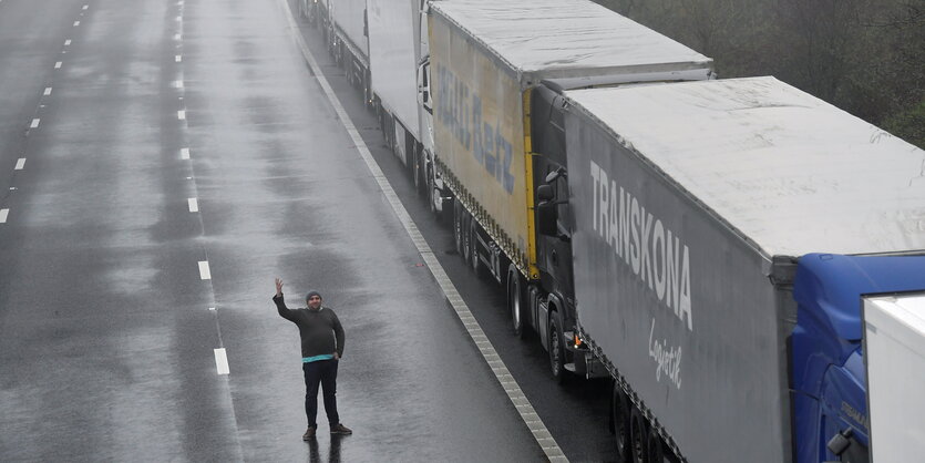 Ein Mann Winkte neben einer Lkw-Schlange stehend.