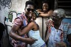 Der cubanische Sänger Cimafunk lacht in die kamera und 3 Frauen lachen mit ihm