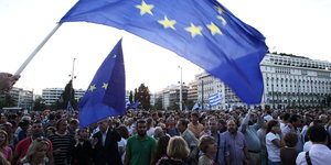 Menschen stehen unter einer Europa-Flagge vor dem griechischen Parlament