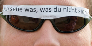 "Ich sehe was, was Du nicht siehst und das ist ein Aufstand" steht auf einem Zettel, den sich ein Mann am 26.07.2014 bei einer Protestkundgebung vor dem "Dagger Complex" des US-Geheimdienste NSA in Griesheim bei Darmstadt an seine Brille geklebt