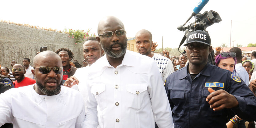 George Weah in weißem Hemd umgeben von Menschen.