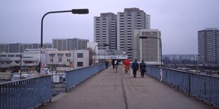 Eine Brücke in Marzahn mit Hochhäusern im Hintergrund - Menschen gehen über die Brücke, darunter ein Weihnachtsmann