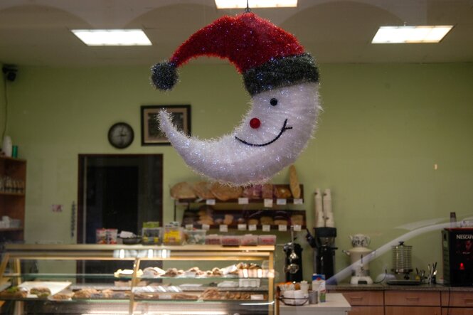 Ein türkischer Bäcker mit seiner Auslage - darüber baumelt ein Mond in einem Weihnachtskostüm