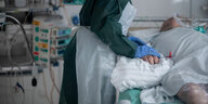 Eine Pflegekraft hält einen Patienten im Krankenhaus die Hand