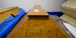 Ein Sarg auf dem geschrieben steht: Achtung Covid-19