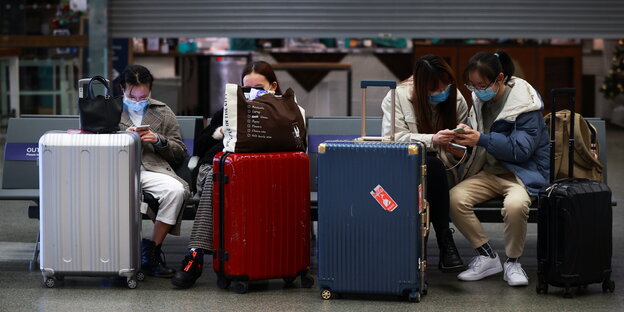 Reisende sitzen mit ihren Koffern im Eurostar Terminal in London