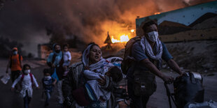 Menschen fliehen vor einem Feuer im Hintergrund