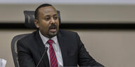 Der Ministerpräsident von Äthiopien Abiy Ahmed sitzt an einem Rednerpult. Er trägt einen Anzug und eine Rote Krawatte.