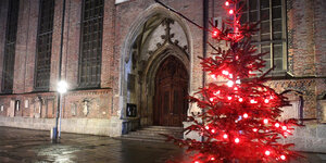 Weihnachtsbaum mit roter Beleuchtung vor dem Eingang der Münchner Frauenkirche