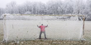 Person im Fußballtor vor verscheniter Landschaft