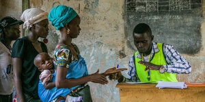 Eine Frau mit einem Kind auf dem Rücken in Bangui gibt ihre Stimme ab