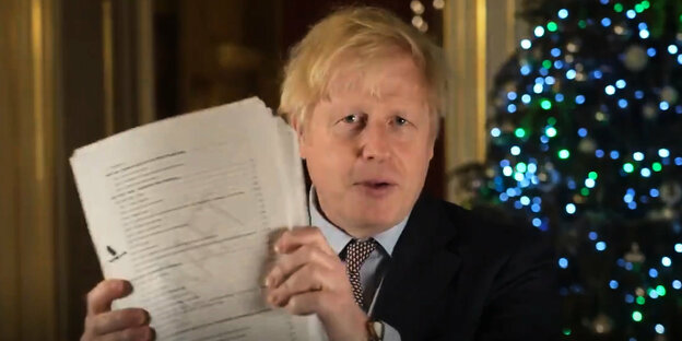 Boris Johnson hält ein Dokument hoch