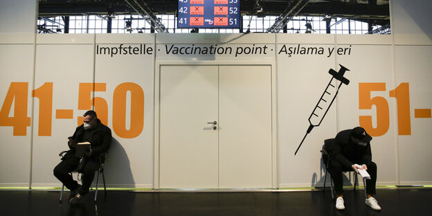 Zwei Männer warten im Impfstoffzentrum Arena Treptow auf ihre Impfung gegen das Coronavirus