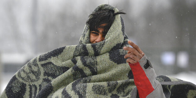 Ein Migrant hüllt sich in eine Decke, während er im Lager Lipa im Nordwesten Bosniens durch den Schnee geht