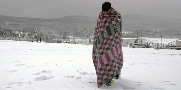 Ein Mann läuft in eine Decke eingewickelt durch den Schnee