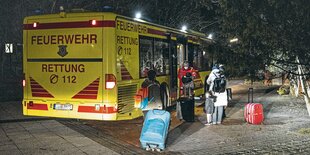 Geflüchtete steigen in einen Feuerwehrbus.