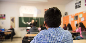 Ein Junge in einem Klassenzimmer schaut an die Tafel