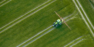 Traktor beim Einsatz von Pflanzenschutzmitteln auf einem Feld aus der Vogelperspektive