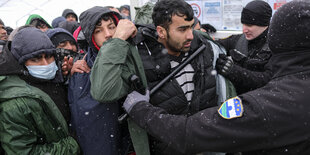 Menschen im Schneefall werden von Polizeikräften mit Schlafstöcken zurückgedrängt